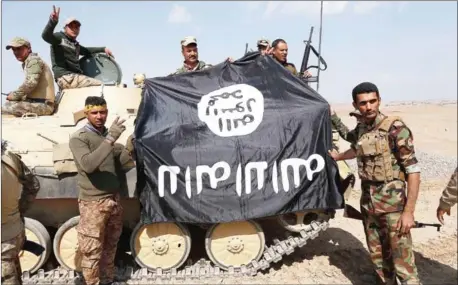  ?? MOHAMMED SAWAF/AFP ?? Iraqi government forces hold an Islamic State flag as they advance in the village of Badush some 15 kilometres northwest of Mosul during the ongoing battle to retake the city’s west on March 8.