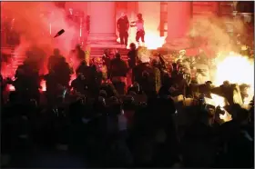  ?? (AP/Darko Vojinovic) ?? Protesters clash with riot police Friday on the steps of the Serbian parliament in Belgrade. More photos at arkansason­line.com/711covid/.