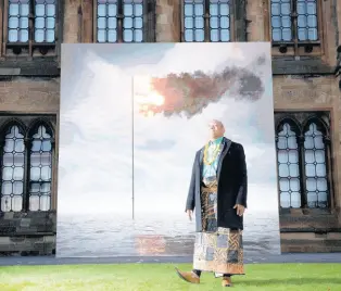  ?? AP ?? Tongan activist Uili Lousi stands alongside ‘Flare Oceania 2021’, created by artist John Gerrard, a real-time moving image showing a simulation of the seas around Tonga with the flag/flare embedded in it, displayed on the South Facade of the University of Glasgow to mark Ocean Day, at the COP26 climate summit, in Glasgow, Scotland.