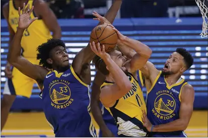  ?? PHOTOS BY JEFF CHIU — THE ASSOCIATED PRESS ?? Indiana Pacers forward Domantas Sabonis, middle, shoots between Warriors center James Wiseman (33) and guard Stephen Curry (30) during the first half on Tuesday.