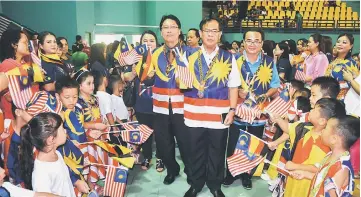  ??  ?? Jamit is welcomed by flag-waving pupils at the Bletih Stadium. Behind him at left is Bukit Mabong District Officer Douglas Pungga.