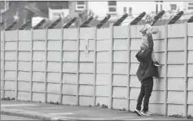  ?? The Associated Press ?? A man holds a child to look over a fence into Liverpool’s Melwood training ground after the English Premier League announced soccer players can return to training in small groups as the coronaviru­s lockdown was eased starting Tuesday.