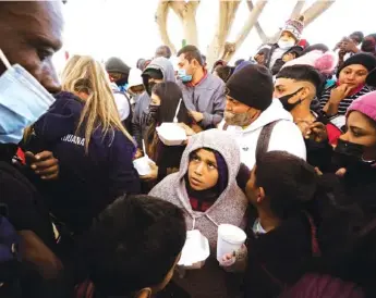  ?? AP PHOTO/GREGORY BULL ?? Asylum seekers receive food as they wait for news of policy changes at the border Friday in Tijuana, Mexico. After waiting months, and sometimes years in Mexico, people seeking asylum in the United States were allowed into the country starting Friday as they wait for courts to decide on their cases.