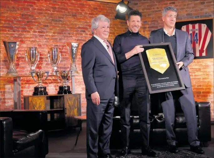  ?? ?? Enrique Cerezo, presidente del Atlético, y Miguel Ángel Gil Marín, consejero delegado, entregan a Simeone una placa bañada en oro por sus 613 partidos en el banquillo rojiblanco.