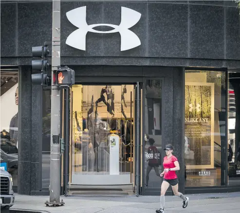  ?? CHRISTOPHE­R DILTS / BLOOMBERG ?? A woman in Chicago jogging by Under Armour, which must improve and expand its footwear business to counter growing market share from competitor Adidas.