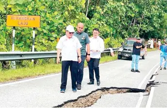  ?? — Ukas photo ?? Uggah (front) takes a closer look at the cracked section of the Ulu Layar Road.
