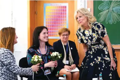  ?? The Associated Press ?? ■ First lady Jill Biden, right, gives flowers to teacher Anastasia Konolovalo­va, left, and Svitlana Gollyak, a mother who had to leave her home in Ukraine, during a visit to the Scoala Gimnaziala Uruguay, or Uruguay School, in Bucharest Romania, on Saturday. Biden visited several classrooms to visit with children and the educators who are helping teach displaced Ukrainian children.