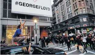  ?? BRYAN SNYDER • REUTERS ?? Passengers in car cheer as protestors rally against the death in Minneapoli­s police custody of George Floyd, beneath a billboard with his name on it, in Boston, Mass. on Sunday.