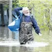  ?? RYAN REMIORZ/THE CANADIAN PRESS ?? Michel Vezina makes his way through the flooded streets Monday in DeuxMontag­nes, Que.