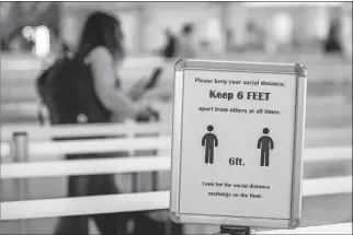  ??  ?? A passenger walks past a sign enforcing social distancing guidelines July 26 at Dallas Love Field airport in Dallas. [LYNDA M. GONZALEZ/ THE DALLAS MORNING NEWS VIA TRIBUNE NEWS SERVICE]