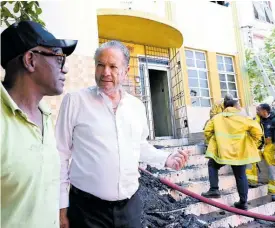  ?? ?? Tom Tavares-Finson (right), president of the Senate, chat with fellow attorney Wentworth Charles in the fire’s aftermath.