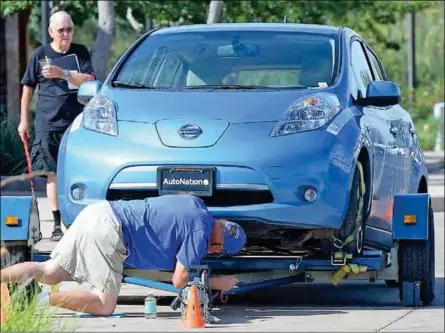  ?? Buy these photos at YumaSun.com PHOTOS BY RANDY HOEFT/YUMA SUN ?? FRANK MENOR CHECKS OUT THE UNDERSIDE OF A NISSAN LEAF ELECTRIC CAR in the parking lot at the Pivot Point Conference Center during Monday morning’s electric vehicles and charging infrastruc­ture, Plugin Around Arizona workshop presented by the Tucson...