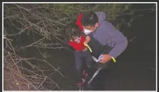  ?? (AP/Dario Lopez-Mills) ?? A father helps his daughter after they were smuggled on an inflatable raft across the Rio Grande in Roma.