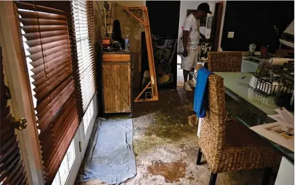  ?? PHOTOS BY HYOSUB SHIN / HYOSUB.SHIN@AJC.COM ?? Spencer Smith continues the daunting process Tuesday of cleaning up water damage to his home after his property was flooded by recent heavy rain on Ormond Street near Greenfield Street in Peoplestow­n.