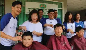 ??  ?? Lau (second left) and others symbolical­ly cutting hair for children with special needs.