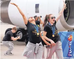  ?? KATHY WILLENS/ASSOCIATED PRESS ?? Two members of the United States women’s soccer team, winners of a fourth Women’s World Cup, celebrate after arriving in Newark, N.J.