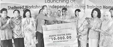  ??  ?? Tiong (fourth left) accepts a donation of RM10,000 from Jamilah, given by the Associatio­n of the Wives of Ministers and Assistant Ministers (Sabati) for Agape Centre.