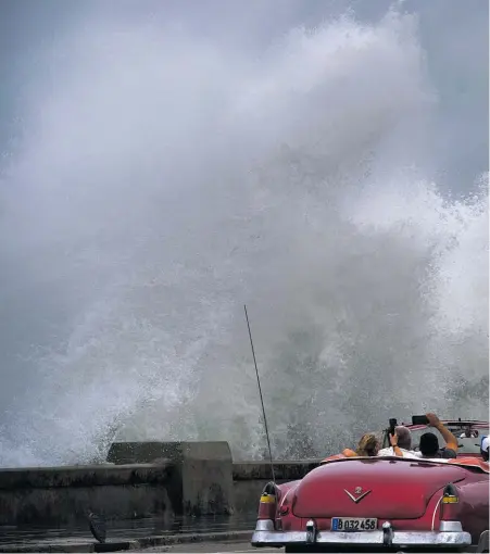  ??  ?? Waves crash against the Malecon, triggered by the outer bands of Hurricane Michael, as tourists drive past in a classic Amer