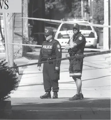  ?? CRAIG ROBERTSON / POSTMEDIA NEWS ?? Police officers stand guard in laneway north of Toronto’s Danforth Avenue after a mass shooting on July 23.