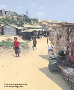  ??  ?? Children walk past food stalls at the Kutupalong camp.