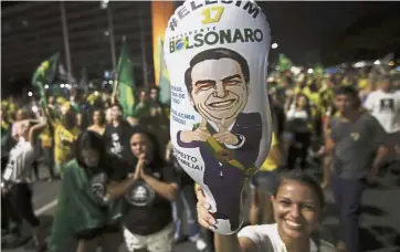  ??  ?? New era begins:A supporter of Bolsonaro holding a balloon with his image during a celebratio­n in front of the National Congress in Brasilia.— AP