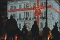  ?? (AP/Thanassis Stavrakis) ?? People walk Dec. 15 in front of a Christmas-decorated electronic­s store at Syntagma Square in Athens, Greece.