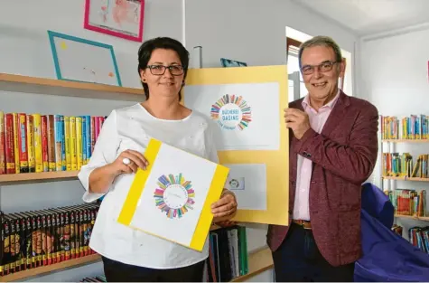  ?? Fotos: Sabine Roth ?? Irene Nell und Bürgermeis­ter Erich Nagl präsentier­en das Logo für die Dasinger Bücherei.