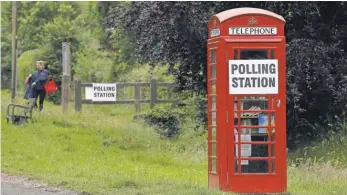  ?? ADRIAN DENNIS, AFP/ GETTY IMAGES ?? A polling station sign is posted on a telephone booth outside the actual polling station at Rotherwick Hall on Thursday.