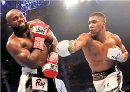  ??  ?? NICK POTTS/PA Anthony Joshua (R) lands a right hook on Carlos Takam before winning on a technical knockout in the 10th round in Cardiff’s Principali­ty Stadium on October 28, 2017.