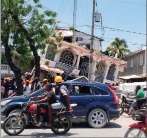  ?? (AP/Delot Jean) ?? People view the damage to the Petit Pas Hotel in Les Cayes, Haiti, after an earthquake struck Saturday, flattening buildings and trapping people under rubble in at least two cities. The hotel likely was full of people visiting for festivitie­s to celebrate the town’s patron saint, a native of the city said.