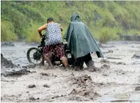  ?? Reuters ?? Residents push a motorcycle across a river with mudflows from Mount Mayon volcano in Albay province on Saturday. —