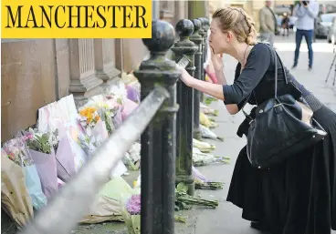  ?? JEFF J MITCHELL / GETTY IMAGES ?? A woman reflects by the flowers left in Manchester’s St. Ann Square on Tuesday, a day after a suicide bombing at a pop concert that killed 22 people in the worst terror incident on British soil since the London bombings of 2005.