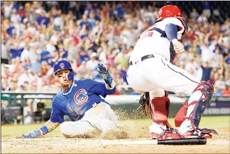  ??  ?? Chicago Cubs’ Javier Baez (left), slides home to score against Washington Nationals catcher Matt Wieters (right),
during the eighth inning of a baseball game on June 26, in Washington.