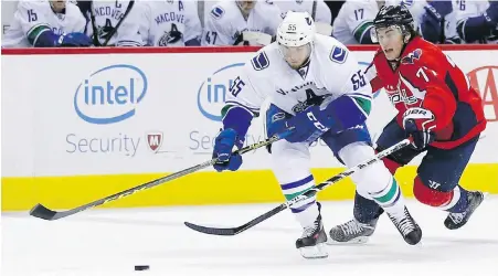  ??  ?? Canucks defenceman Alex Biega fends off Capitals winger T.J. Oshie during the first period in Washington.