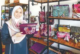  ?? BERNAMAPIC ?? Wan Nur Akmal showing batik bags created by her workers. –