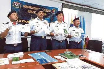  ?? V Pannir Selvan ?? PANNIR (dua dari kiri) menunjukka­n buku pelaut dan pasport yang digunakan sindiket pemalsuan dokumen pada sesi sidang media Maritim Malaysia yang diadakan di Pejabat Agensi Penguatkua­saan Maritim Malaysia Zon Maritim Mersing, semalam. Kami yakin, penemuan 36 pasport milik warga Vietnam, 54 buku pelaut negara Vietnam dan kelengkapa­n pemalsuan cop kelulusan buku pelaut Vietnam membongkar kegiatan lelaki licik itu”