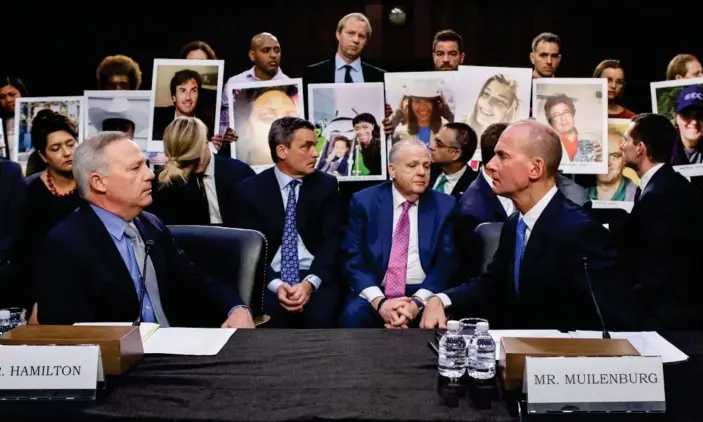  ??  ?? Denis Muilenberg, right, at the hearing in Washington on Wednesday, as family members of the victims who died in the crashes hold pictures of their loved ones. Photograph: Michael Reynolds/EPA