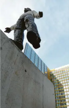  ??  ?? Balanciere­n auf der Mauer: Ein Kunstwerk von Stephan Balkenhol vor dem SpringerHa­us, das einst direkt an der Mauer stand.