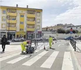  ?? EL PERIÓDICO ?? Operarios municipale­s pintan la señalizaci­ón vial en la calle Almazara.