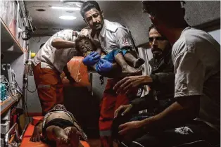  ?? Ismael Abu Dayyah/Associated Press ?? Palestinia­n medics in an ambulance evacuate wounded children after an Israeli attack early Saturday in Rafah, Gaza Strip. Israeli strikes killed at least six people.