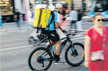  ?? Alejandro MartÍnez VÉlez / EP ?? Un repartidor fa servir el telèfon mòbil mentre condueix una bici per un carrer cèntric de Madrid