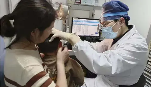  ?? ?? Le Dr Yilai Shu examine un jeune patient à l'hôpital de l'université de Fudan à Shanghai, en Chine, après une procédure de thérapie génique pour une surdité héréditair­e.