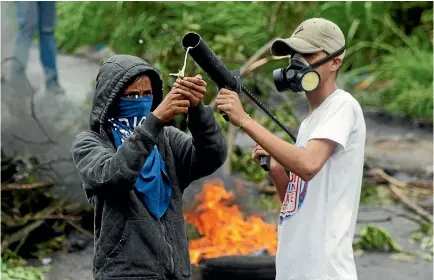  ?? PHOTO: REUTERS ?? Opposition supporters load a home-made firebomb thrower as they clash with security forces during a protest against Venezuelan President Nicolas Maduro’s government in Palmira yesterday.