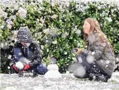  ?? WILL LESTER/THE ORANGE COUNTY REGISTER VIA AP ?? Brody Mielke, left, 10, and his older sister Braelynn, 12, make a snowman as snow falls at approximat­ely the 1,700 foot level in front of their Fontana, Calif., home in Hunters Ridge on Saturday.