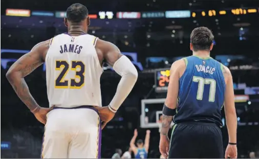  ??  ?? LeBron James y Luka Doncic observan un lanzamient­o de tiro libre, en un partido entre Los Angeles Lakers y Dallas Mavericks.