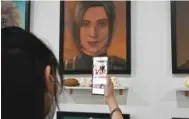  ??  ?? Anime fan Kullanit Assawawong­kasem looking at an oil portrait of deceased Attack on Titan (Shingeki no Kyojin) character Sasha (Potato Girl) Braus.