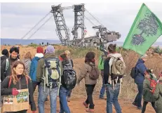  ?? FOTO: DPA ?? Am Hambacher Tagebau stehen Aktivisten kurz vor der Grube. Im Hintergrun­d ist der Braunkohle-Bagger bereits gestoppt worden.