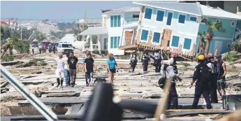  ?? Reuters ?? Left: First responders and residents walk along a main street following the hurricane Michael in Mexico Beach, Florida.