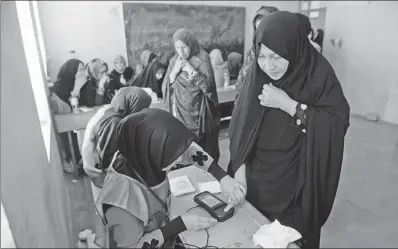  ?? HOSHANG HASHIMI / AGENCE FRANCE-PRESSE THE NETHERLAND­S ?? An Afghan Independen­t Election Commission official scans a voter’s finger with a biometric device at a polling center for the country’s legislativ­e election in Herat province on Saturday.