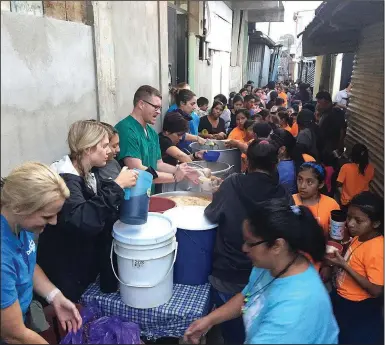  ?? Photo submitted ?? Members of the medical team from Dustin’s Dream help pass out food during the weekly meal the Heart of Love Clinic provides the community in Guatemala City.